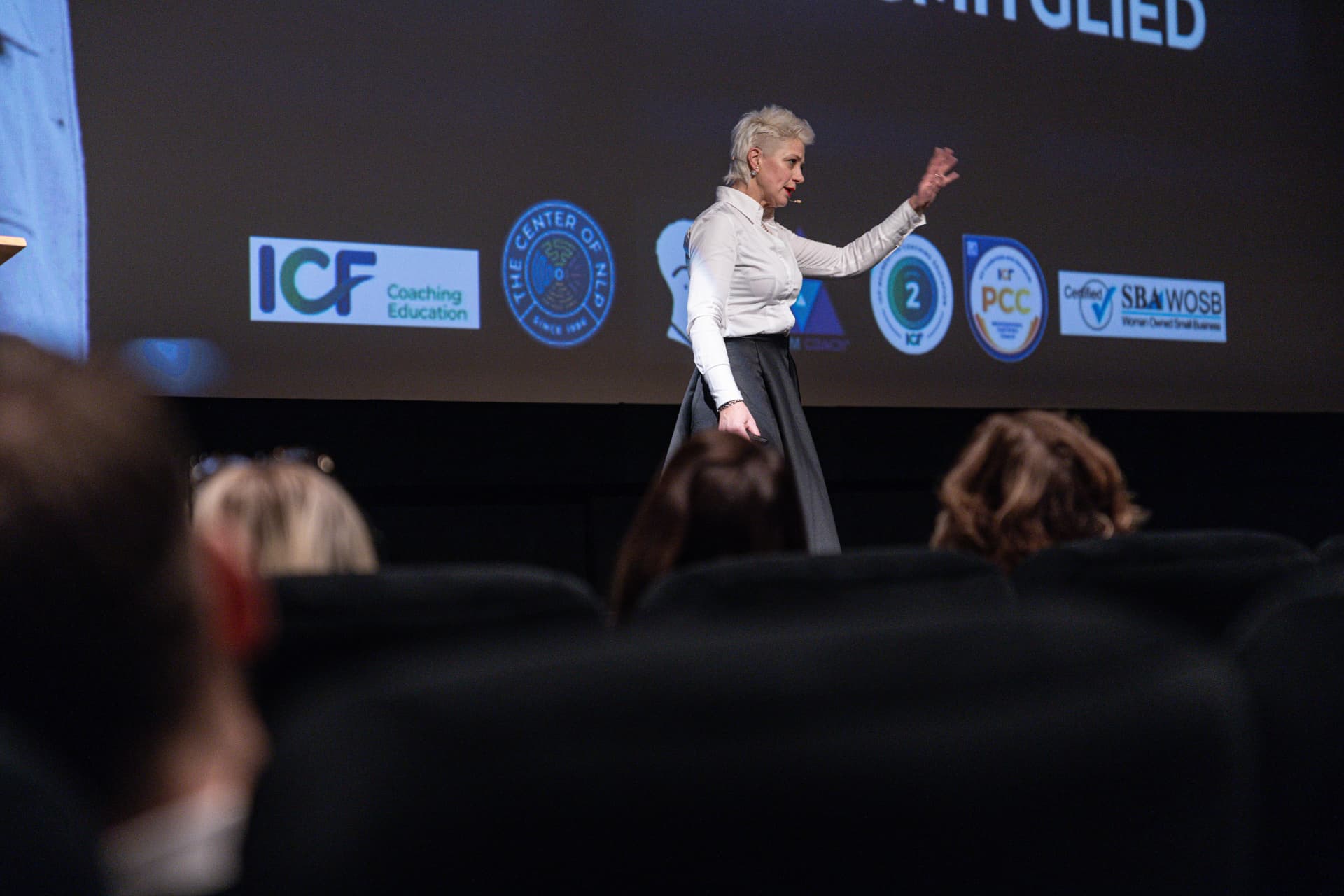 Brigitta Hoeferle speaking on stage to an audience of business owners